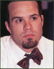 Player Mike Long looking pensive in a white shirt with an unevenly tied bow-tie sitting askew around his neck.